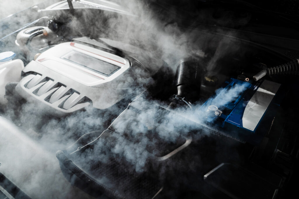 White steam coming from an overheating car engine bay requiring mechanical repairs